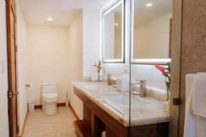 Modern bathroom with double sink, large mirror, and mountain view window.