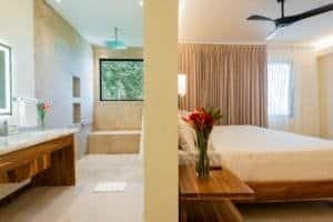 Elegant bedroom with rainforest view and modern bathroom in Dominical estate.