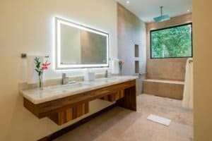 Modern bathroom with large window overlooking lush rainforest in Dominical.