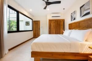 Modern bedroom with wooden accents, large window, and mountain view in Dominical.
