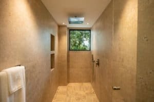 Modern rainforest shower with window view of lush greenery in Dominical estate.