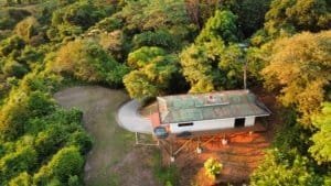 A small house surrounded by lush green trees with ocean and mountain views in Costa Rica.