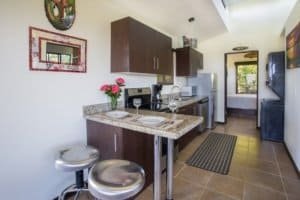 Interior view of a kitchen with dark wood cabinets, granite countertops, and a small dining area.