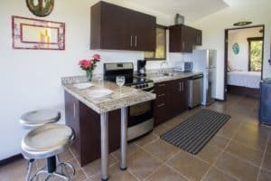 Contemporary kitchen with dark cabinets, granite countertops, and ocean view in Dominical.