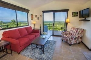 Living room with ocean view, red sofa, patterned armchair, and balcony.