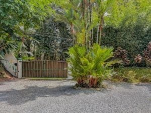 Lush tropical garden with gate and gravel driveway in Dominical.