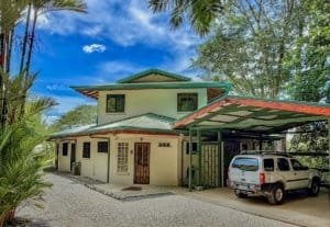Two-story house with carport and lush tropical surroundings in Dominical.