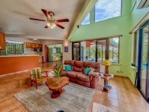 Bright living room with high ceilings, large windows, and tropical decor.