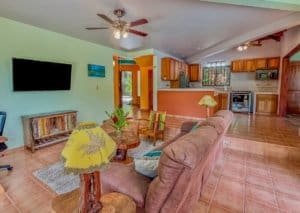 Spacious living room with colorful decor, TV, and open kitchen in Dominical.
