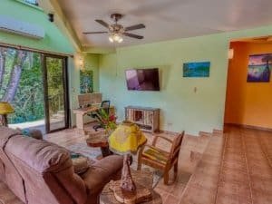 Bright living room with TV, colorful paintings, and sliding door to balcony.