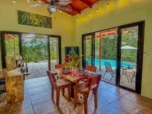 Indoor dining area with large glass doors overlooking pool and greenery.