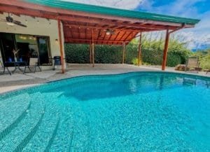 Swimming pool with covered patio and lush greenery in Dominical, Costa Rica.