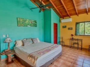 Bright bedroom with colorful walls, wooden ceiling, and tropical decor in Dominical.