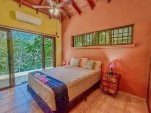 Comfortable bedroom with large windows overlooking lush greenery in Dominical.