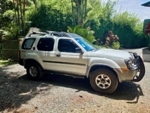 Two 4x4 vehicles parked on gravel near lush greenery in Dominical, Costa Rica.