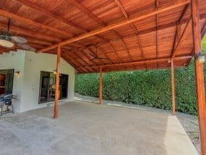 Spacious covered patio with ceiling fans and lush greenery in the background.