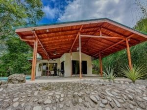 Modern home with large wooden covered porch and natural stone landscaping.