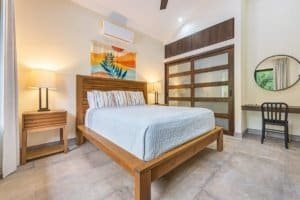 Modern bedroom with wooden furniture, colorful wall art, and natural light in Dominical.