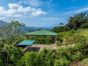Costa Rican home with ocean view, surrounded by lush greenery and mountains.