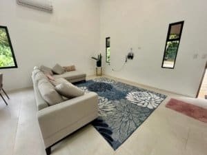 Bright living room with white walls, large windows, and a floral rug in Dominical.