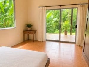 Cozy bedroom with large sliding glass door to lush jungle patio in Dominical.