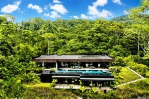 Modern luxury home with infinity pool and lush forest backdrop in Costa Rica.