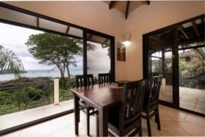 Dining area with ocean view, tropical scenery, and sliding glass doors.