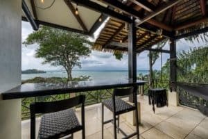Balcony with ocean view, tropical trees, and pool in Dominical, Costa Rica.