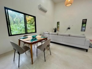 Bright living room with large window overlooking lush greenery in Dominical.