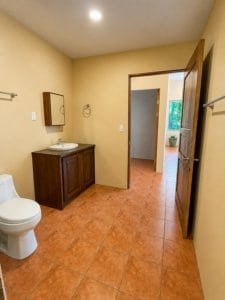 Spacious bathroom with sink, mirror, and toilet in a tropical jungle home.