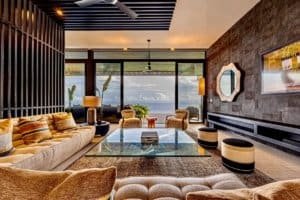 Modern living room with ocean view, stylish furniture, and tropical decor.