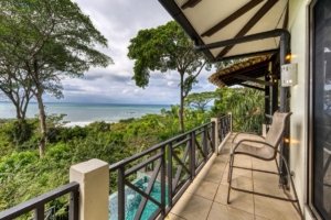 Balcony with ocean view, lush greenery, and tropical trees in Dominical.