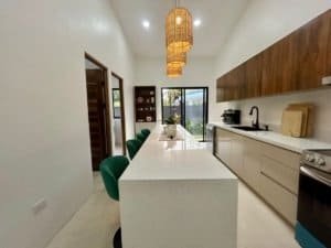 Contemporary kitchen with island, green chairs, and wooden accents in Dominical.