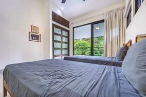 Bright bedroom with large window overlooking lush rainforest in Dominical.