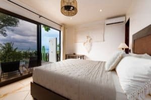 Bedroom with ocean view, balcony, and modern decor in Dominical.