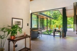 Interior view of a Japanese-style home with large glass windows and lush jungle scenery.