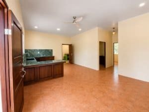 Spacious living area with kitchen and natural light in Dominical jungle home.