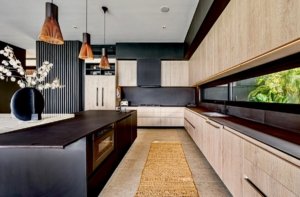 Contemporary kitchen with sleek cabinets and large window overlooking greenery.