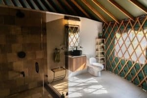 Modern bathroom with walk-in shower, toilet, and wooden lattice walls in Dominical.