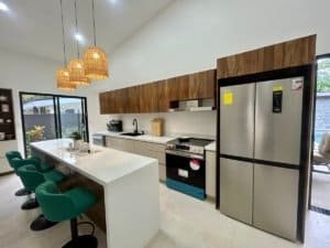 Contemporary kitchen with island, green chairs, and stainless appliances in Dominical.
