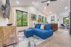 Bright living room with large windows overlooking lush rainforest in Dominical.