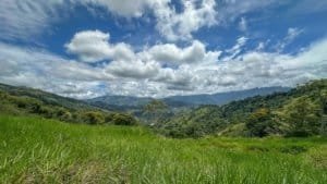 Beautiful lush green hills and mountains under a partly cloudy sky in Dominical.