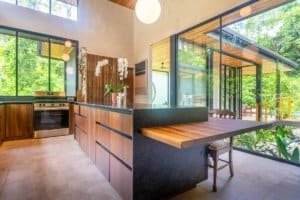Contemporary kitchen with large windows overlooking lush jungle in Dominical.