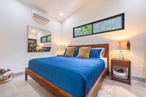 Elegant bedroom with blue bedding, wooden furniture, and rainforest views.