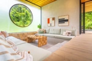 Bright living room with large round window and jungle view in Costa Rica.