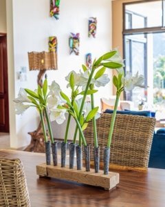 White flowers in a wooden vase on a dining table in a bright living room.