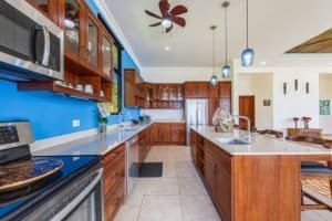 Spacious kitchen with wooden cabinets, blue wall, and stainless steel appliances.