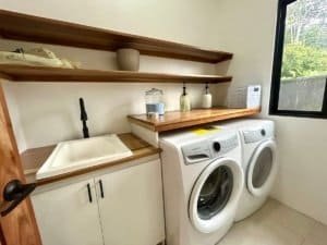 Clean laundry room with washer, shelves, and window in Dominical.