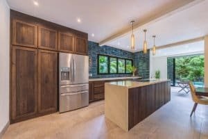 Contemporary kitchen with wooden cabinets, stainless steel fridge, and pool view.