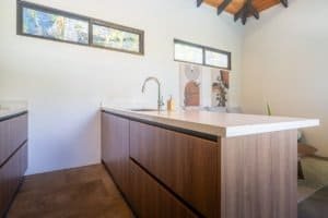 Contemporary kitchen with ocean view windows and wooden cabinets in Costa Rica.